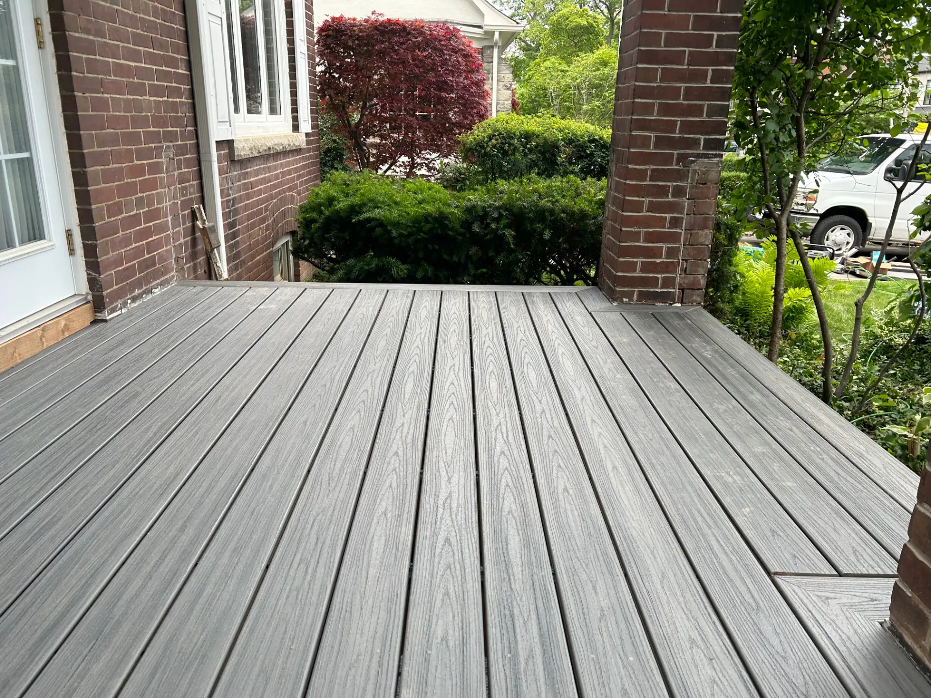 Grey composite deck wrapping a brick home | Leaside